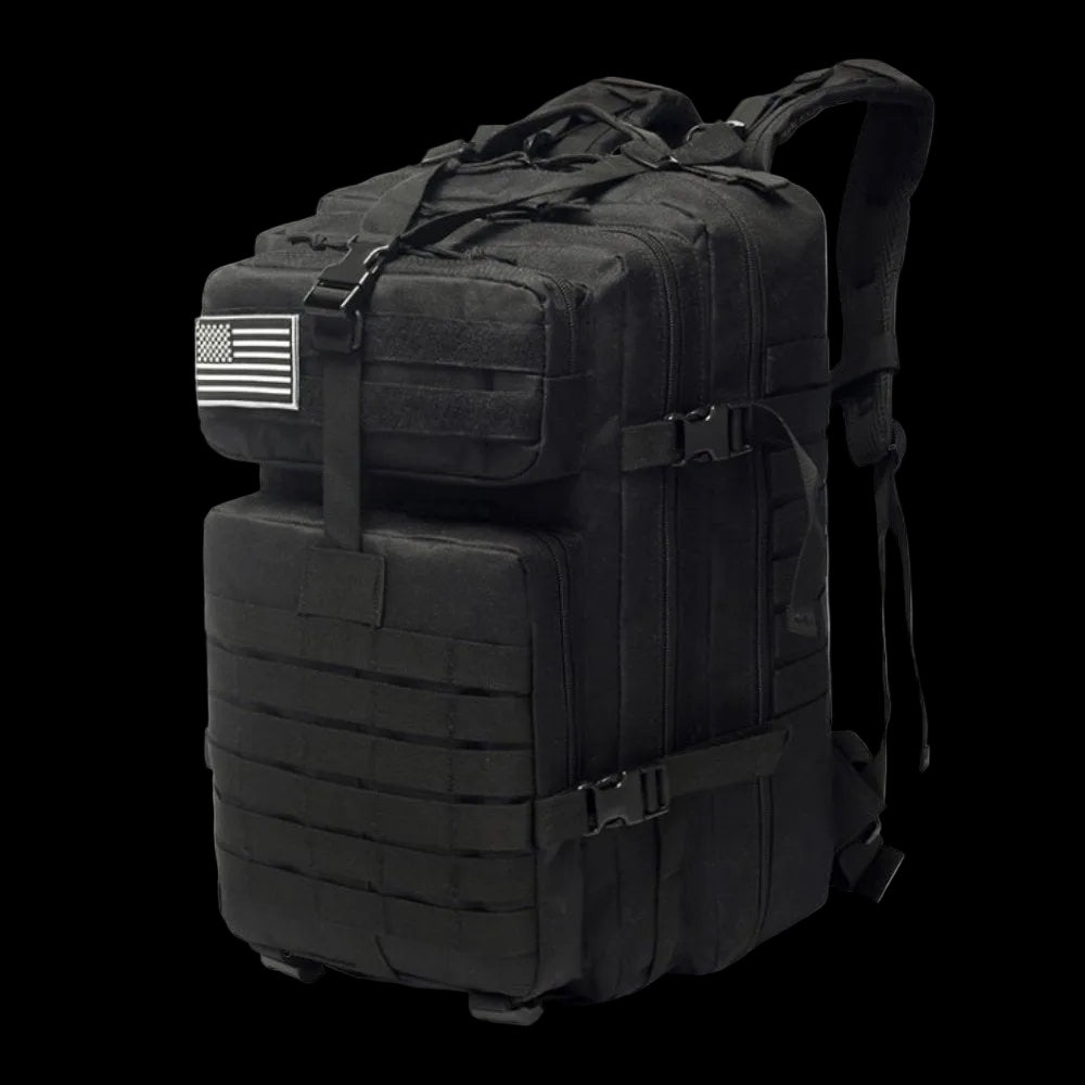 A black tactical military backpack with multiple zippered compartments, MOLLE webbing, compression straps, and a black-and-white American flag patch on the side, shown on a white background.